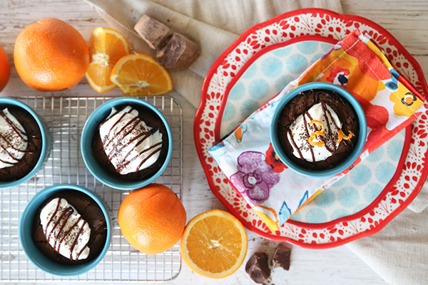 Flourless chocolate orange tarts in light blue ramekins on a table with oranges